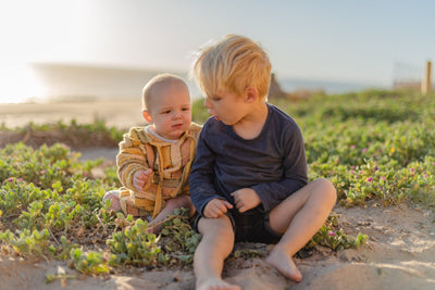 Two young brothers sitting together on a grassy beach dune
