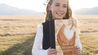 A smiling girl holding The Book of Mormon Storybook